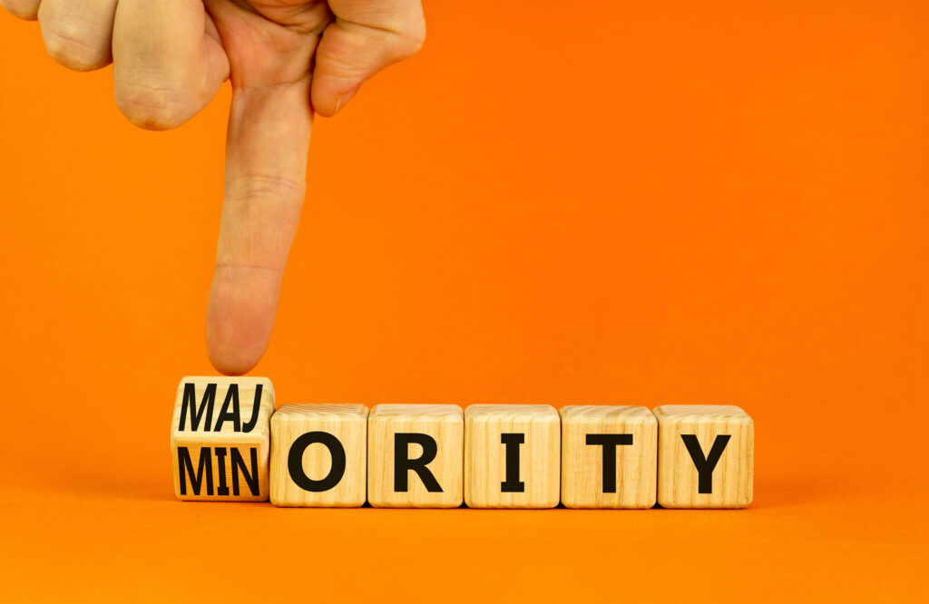 Minority or majority symbol. Businessman turns wooden cubes and changes the concept word Minority to Majority. Beautiful orange background. Minority or majority and business concept. Copy space.