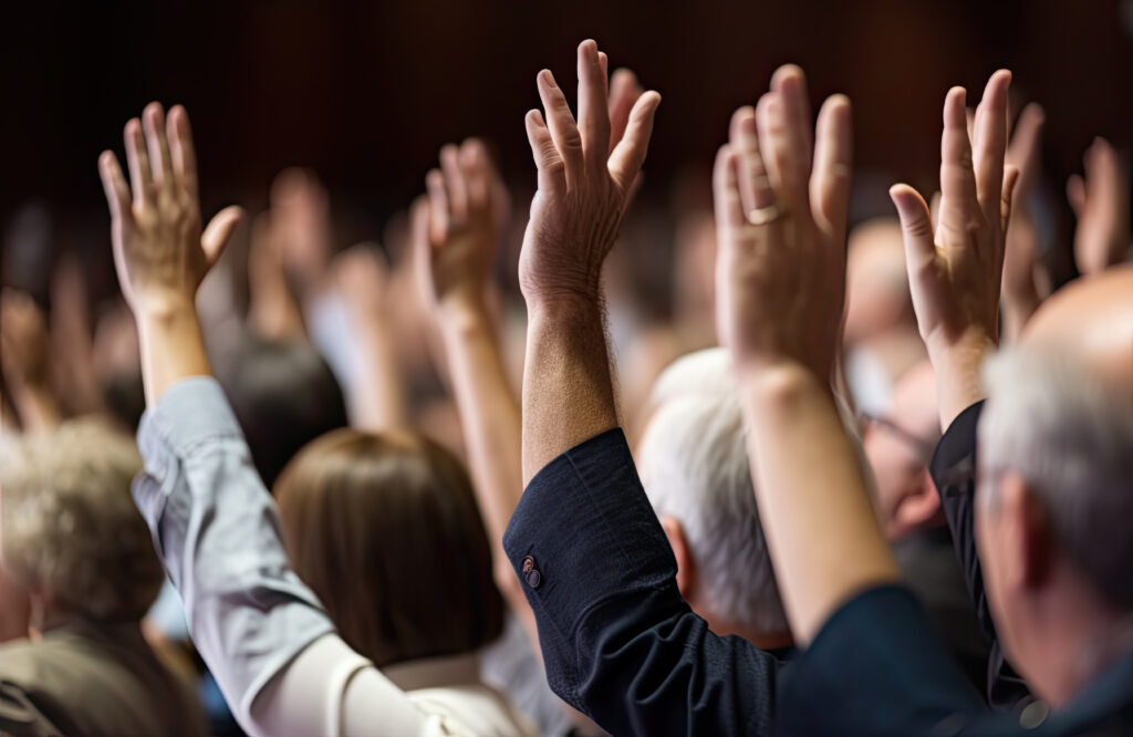 At a professional business seminar, a diverse audience raises th